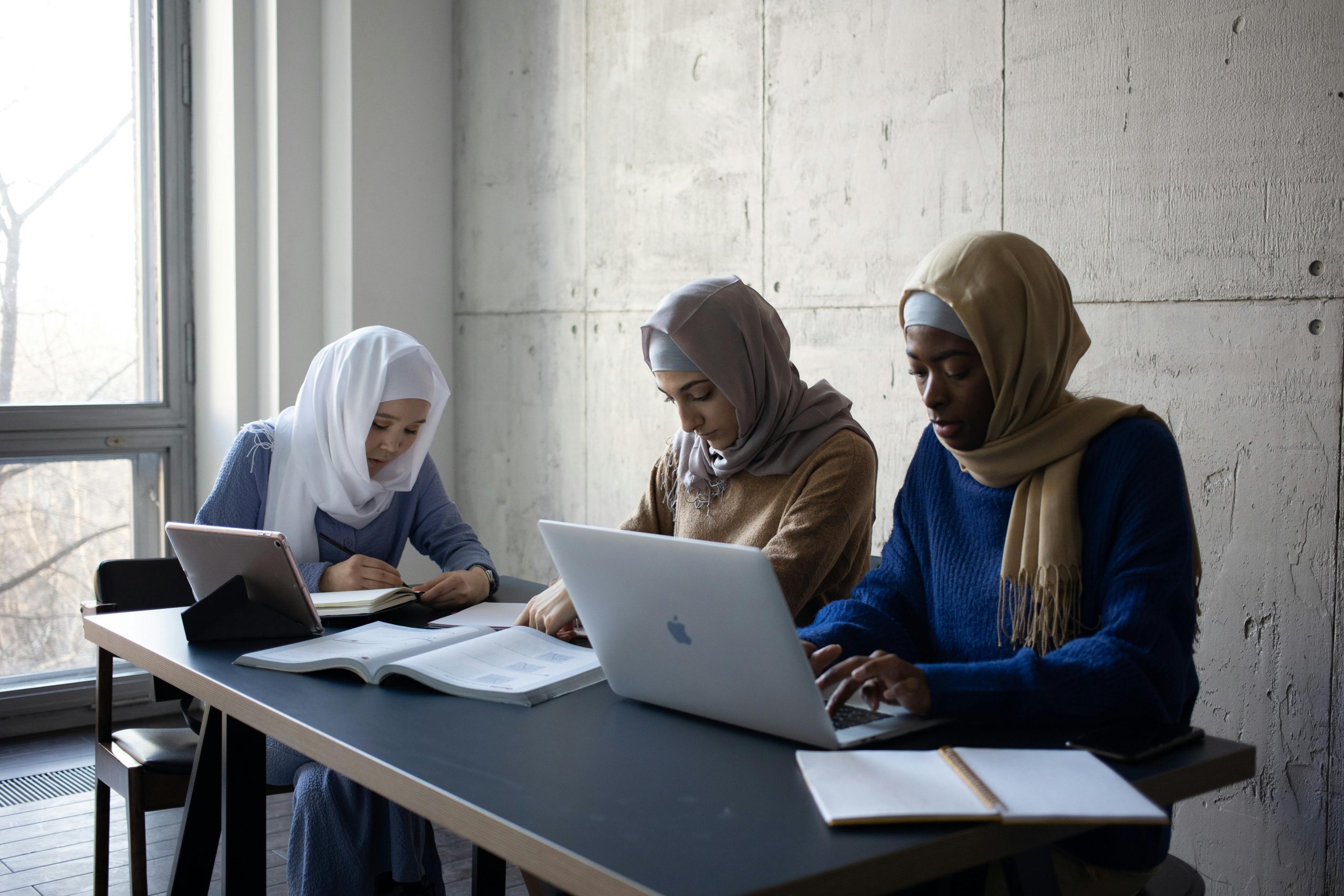 Three Arabian women wearing Hijabs completing an online English course.