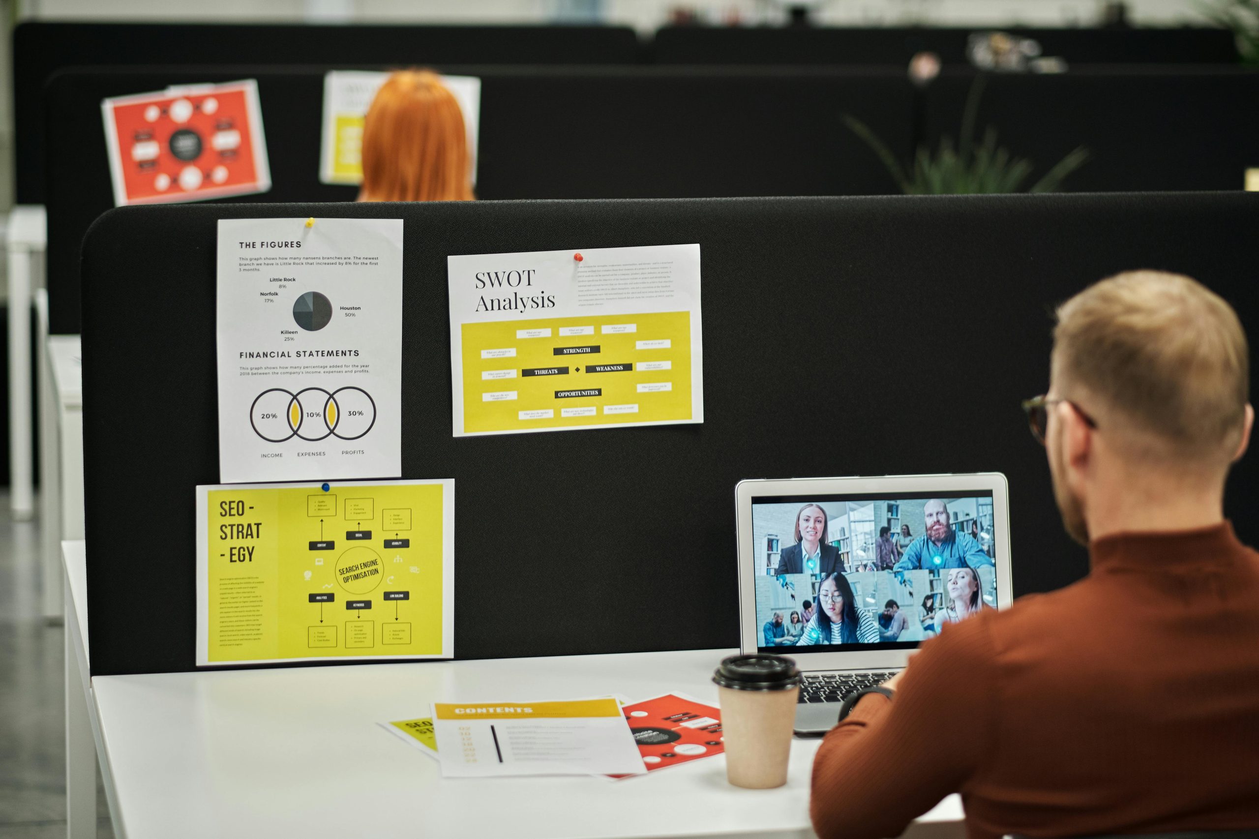 A blonde Swiss man taking a virtual English class at work with four other students.