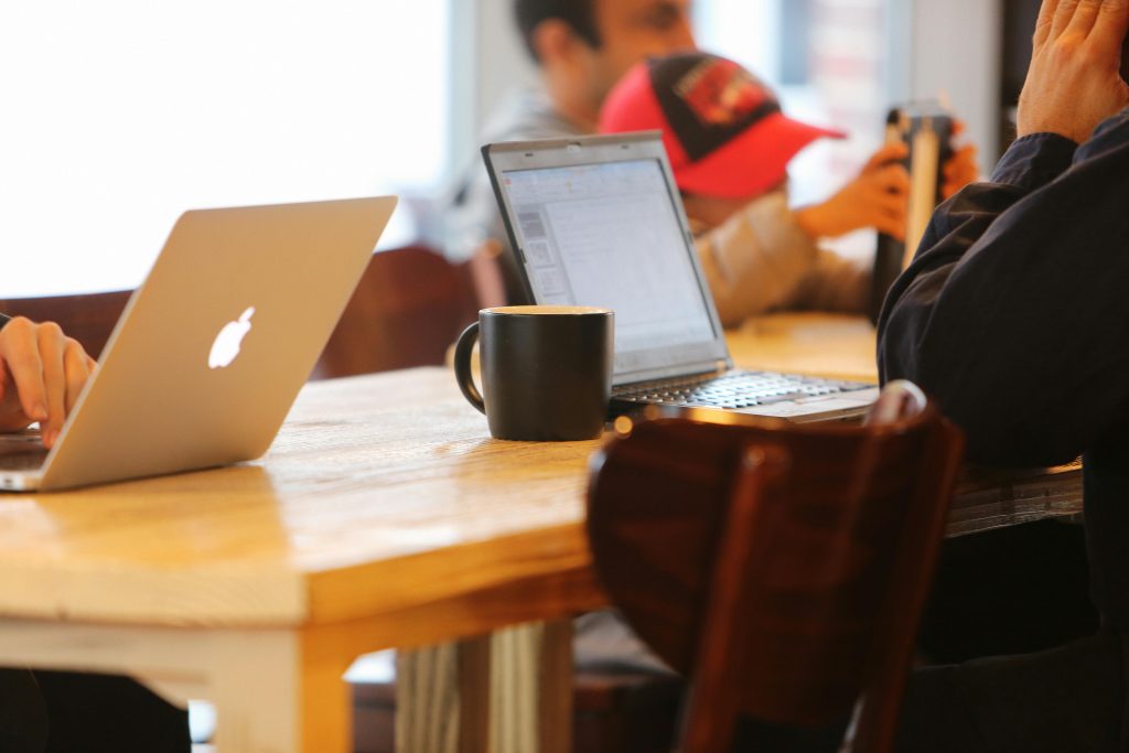 A black mug next to a laptop displaying ESL homework